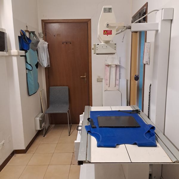Sala radiologia con apparecchio radiografico e camici di protezione
